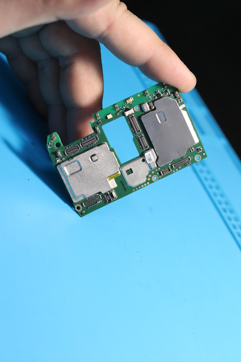 A hand holds a green circuit board.