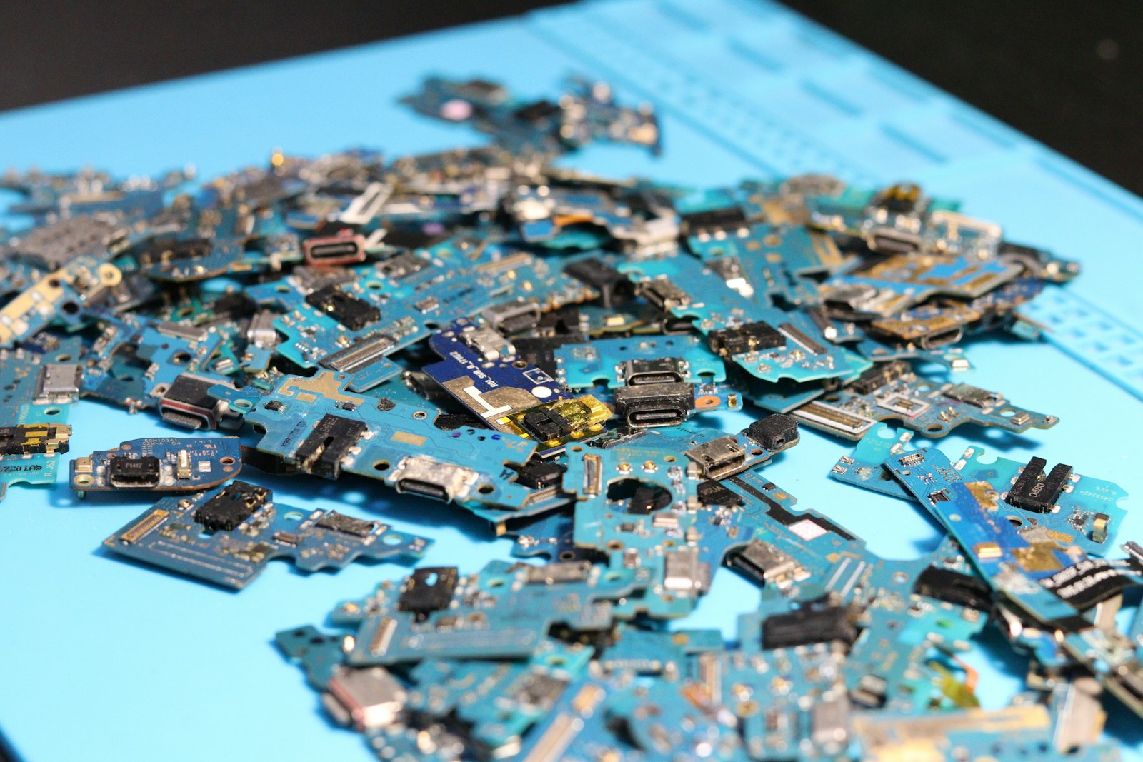 Electronic circuit boards are piled on a blue mat.